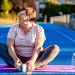 Mulher na menopausa a alongar-se num tapete de yoga ao ar livre, mostrando uma forma natural e energética de aliviar os sintomas.